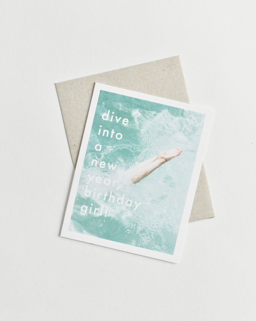 Photo greeting card of legs diving into clear blue water and words “dive into a new year, birthday girl!”