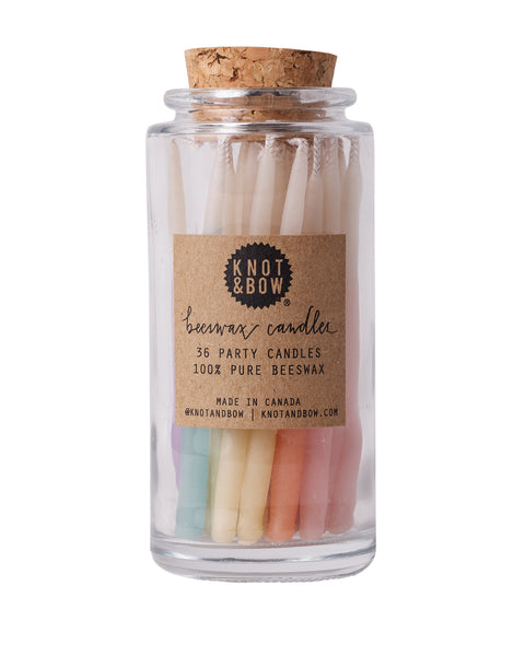 Hand-dipped beeswax candles in assorted colors with an ombre effect, packaged in a glass jar with a cork top.