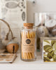 Hand-dipped beeswax candles in a natural pale yellow color, packaged in a glass jar with a cork top.