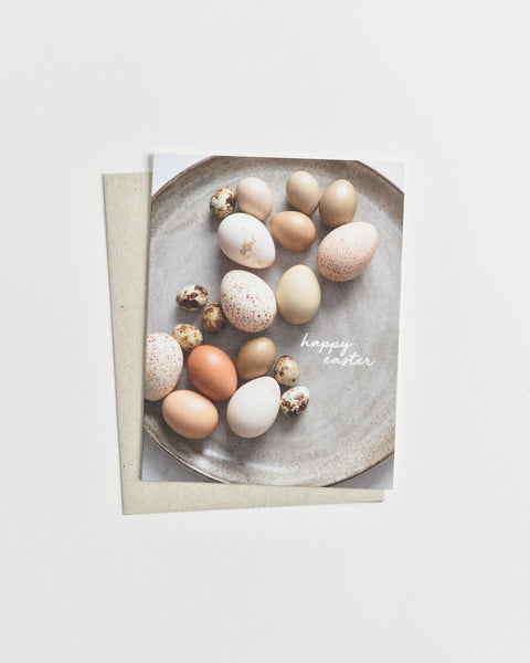 Photo greeting card of assorted brown and white eggs in various patterns and sizes with words “happy easter” in cursive.