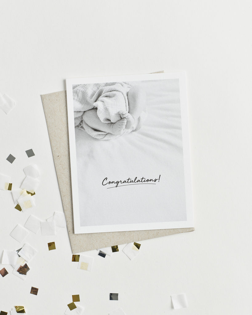 Greeting card with a black and white photo of baby feet and “Congratulations!” in cursive.
