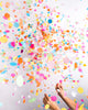 Explosion of assorted rainbow confetti after popping a jumbo confetti balloon.