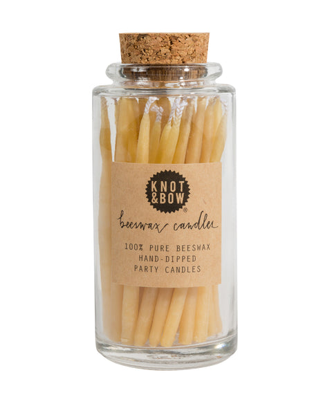 Hand-dipped beeswax candles in a natural pale yellow color, packaged in a glass jar with a cork top.